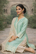 Mint green Neerika Kurta set with intricate embroidery, matching dupatta, and traditional design, worn by a woman sitting gracefully.